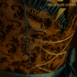 Genuine leather dirndl with brown embossed baroque pattern bodice, cream bell-sleeve blouse, teal satin trim, and chocolate brown pleated skirt