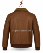 Aviator leather jacket detail showing textured sherpa collar, embroidered aviation chest patch, brown leather grain, and metal zipper.